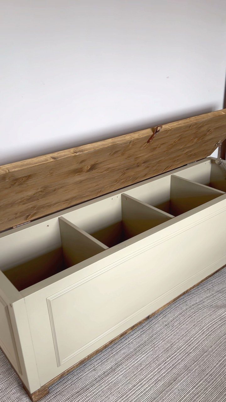 A cream-colored wooden storage bench with an open lid showing four internal compartments.