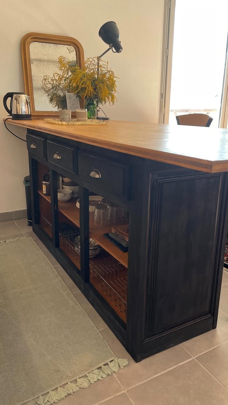 Dark painted wooden sideboard with a light wood top used as a kitchen island.
