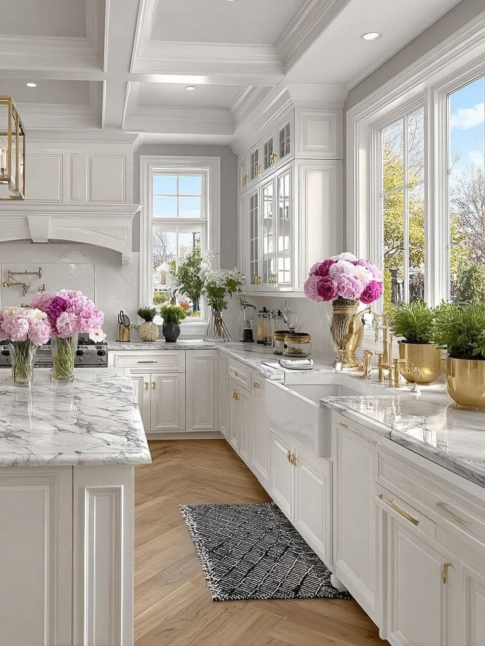 White farmhouse kitchen with marble countertops, shaker cabinets, and a white coffered ceiling.