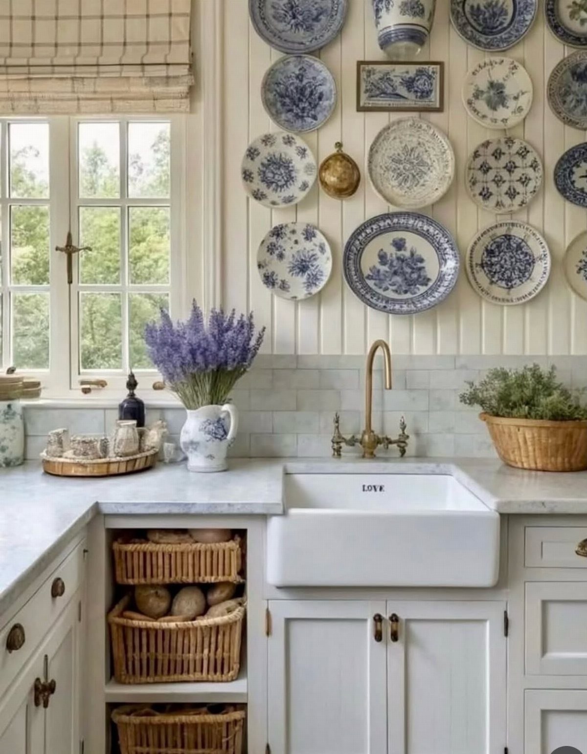 White farmhouse kitchen with blue patterned plates on the wall and lavender in a vase.