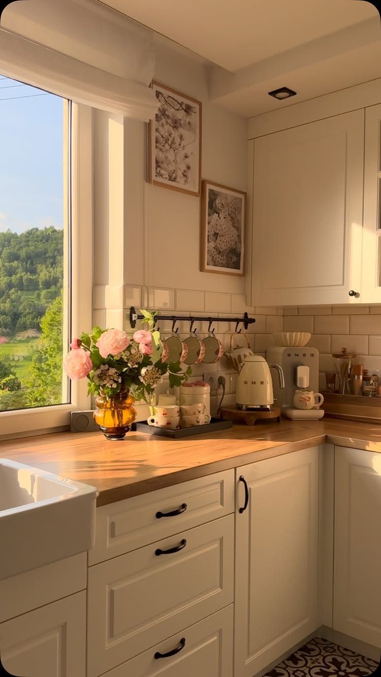White shaker cabinets and a farmhouse sink paired with warm natural wood countertops in a sunlit kitchen.