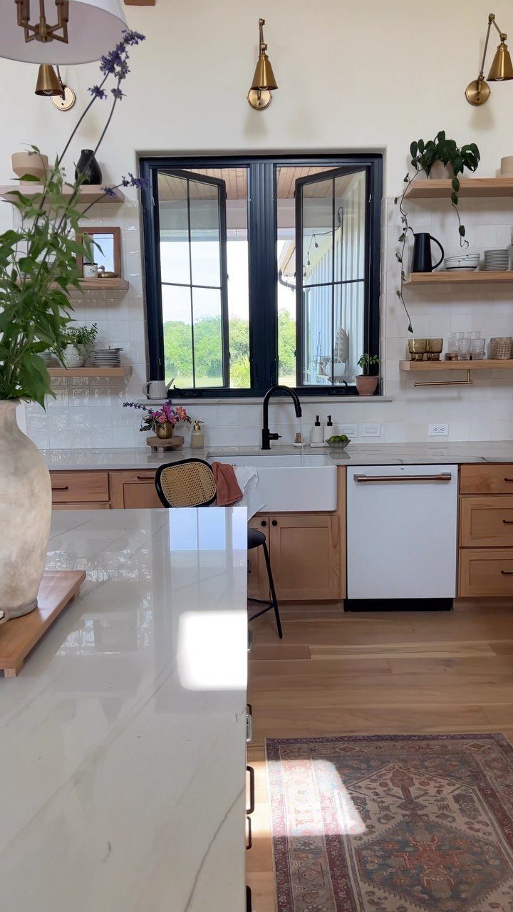 Wooden open shelves holding decorative items on a white kitchen wall above marble countertops.