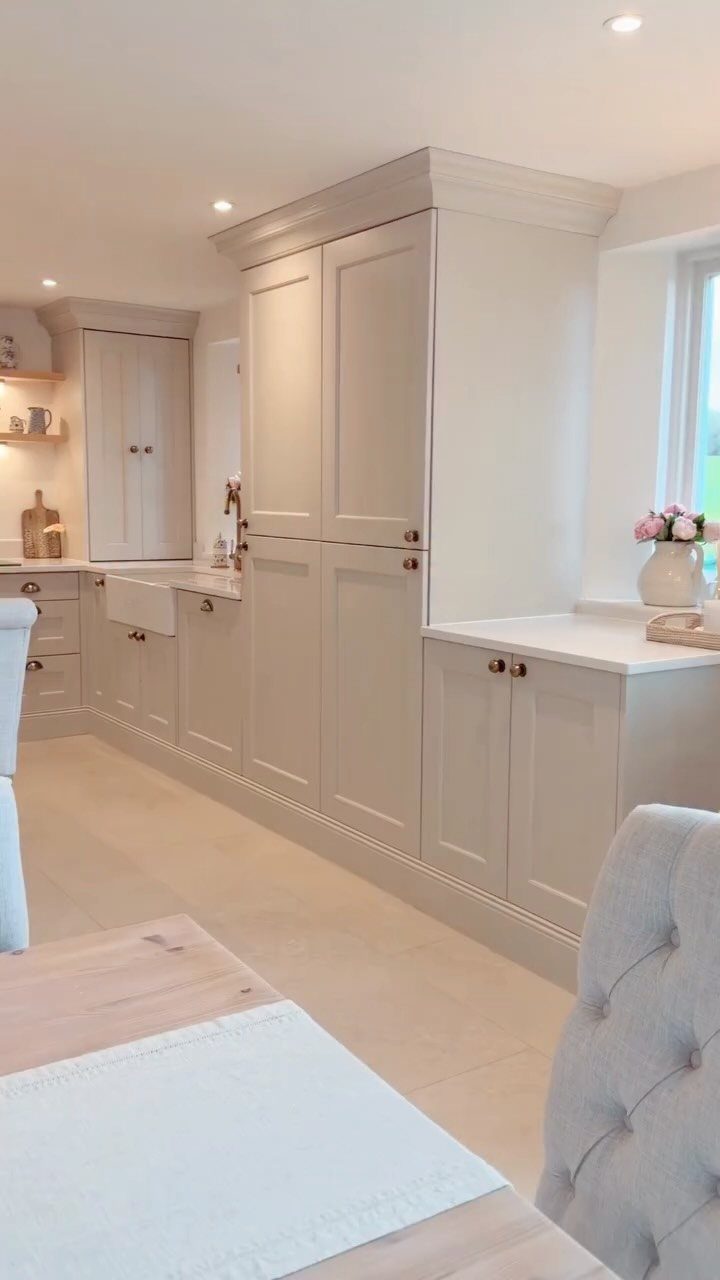 Light grey shaker style kitchen cabinets with white countertops and a farmhouse sink.